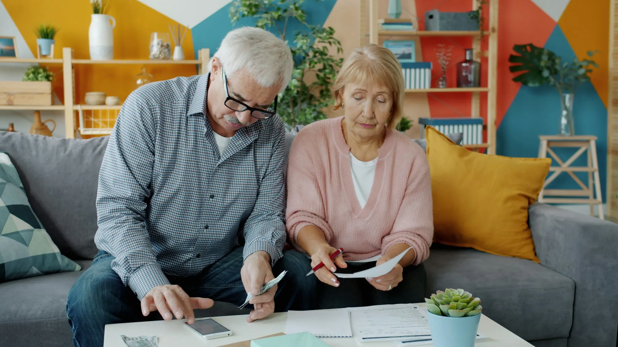 Older couple reviewing paperwork on their sofa